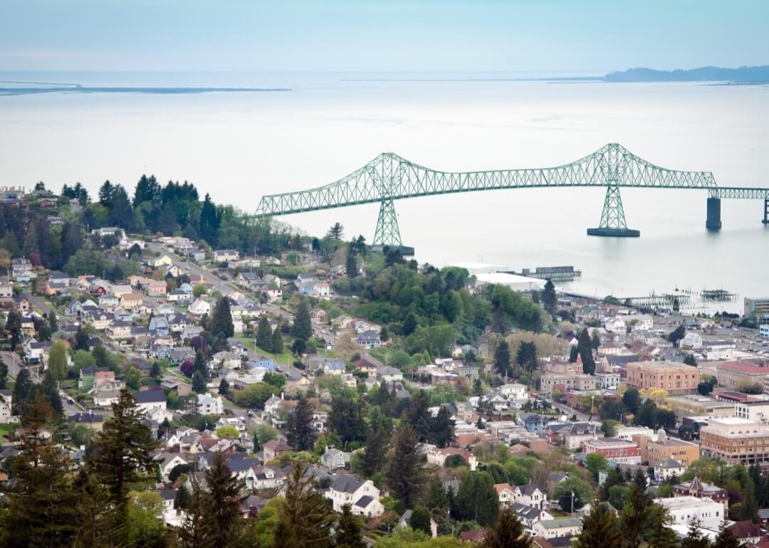 Aerial view of homes in Astoria, Oregon, with a suspension bridge in the background.